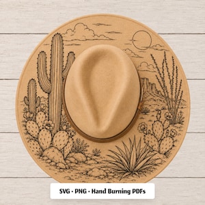 May include: A tan felt hat featuring a black line art desert landscape illustration with cacti, agave, and a sun. The text SVG • PNG • Hand Burning PDFs is printed at the bottom. The hat has a structured crown and a wide brim with a brown band.