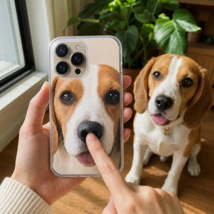 May include: A clear smartphone case featuring a high-resolution photographic print of a beagle dog's face. The design shows the dog's eyes, white muzzle, and black nose, with a finger touching the nose on the case to mimic a playful interaction.