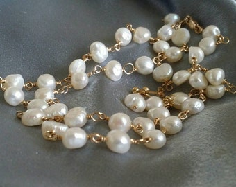 May include: A delicate gold chain necklace with white pearls. The pearls are irregularly shaped and strung together with small gold wire.