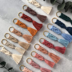Personalized macramé keychains hand-woven from pure cotton cord. Available in a wide range of colors and featuring wooden bead accents, these keychains make a lovely gift for bridesmaids, the maid or matron of honor, flower girls, and the "bride tribe." They also add an elegant touch to bridesmaid proposal boxes.