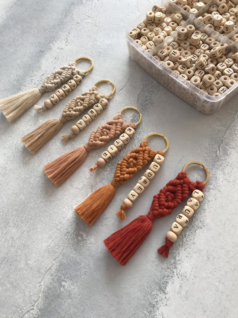 Personalized macramé keychains hand-woven from pure cotton cord. Available in a wide range of colors and featuring wooden bead accents, these keychains make a lovely gift for bridesmaids, the maid or matron of honor, flower girls, and the "bride tribe." They also add an elegant touch to bridesmaid proposal boxes.