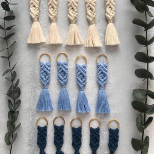 Personalized macramé keychains hand-woven from pure cotton cord. Available in a wide range of colors and featuring wooden bead accents, these keychains make a lovely gift for bridesmaids, the maid or matron of honor, flower girls, and the "bride tribe." They also add an elegant touch to bridesmaid proposal boxes.