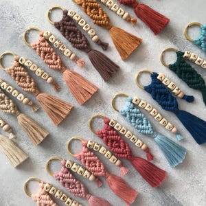 Personalized macramé keychains hand-woven from pure cotton cord. Available in a wide range of colors and featuring wooden bead accents, these keychains make a lovely gift for bridesmaids, the maid or matron of honor, flower girls, and the "bride tribe." They also add an elegant touch to bridesmaid proposal boxes.