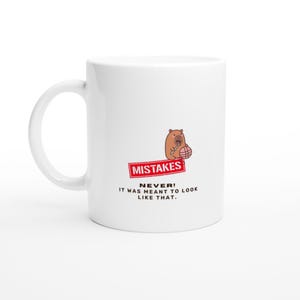 May include: A white ceramic mug featuring a cartoon capybara holding a knitting needle and a ball of yarn. Below the capybara is a red rectangular stamp with the word MISTAKES and the text NEVER! IT WAS MEANT TO LOOK LIKE THAT.