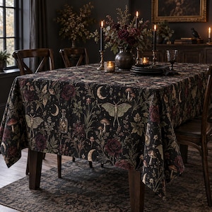 May include: A rectangular tablecloth featuring a dark black background with a repeating pattern of moths, crescent moons, mushrooms, glass potion bottles, and deep red roses. The fabric drapes over a dining table, displaying a botanical theme.