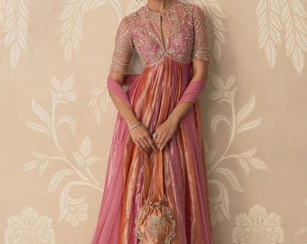 May include: A floor-length gown featuring a pink and orange striped skirt with a matching bodice adorned with intricate gold embroidery and beadwork. The garment includes half-length sleeves, a high neckline with a central slit, and a coordinating drawstring pouch bag.