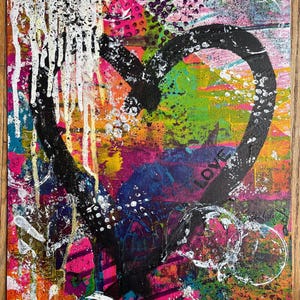 May include: A rectangular canvas painting featuring a large, thick black heart outline centered on a vibrant, multi-colored background. The artwork includes layers of pink, green, orange, and blue paint with white drips, splatters, and the word LOVE.