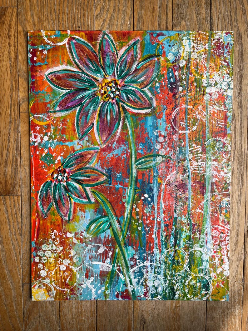 May include: A rectangular canvas painting featuring two stylized flowers with dark teal and purple petals. The background is a vibrant, textured mix of red, orange, and blue paint with white circular patterns and vertical drips throughout the composition.