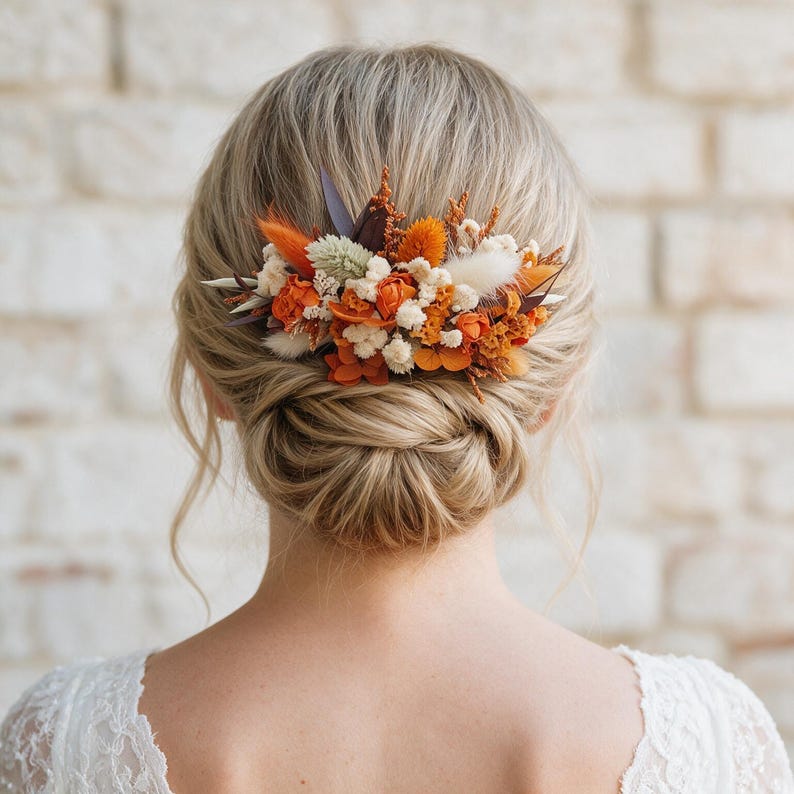 May include: A hair comb featuring an arrangement of dried flowers and foliage in shades of burnt orange, cream, and brown. The decorative piece is secured into a blonde updo hairstyle, showcasing a mix of textures including small blossoms and grasses.