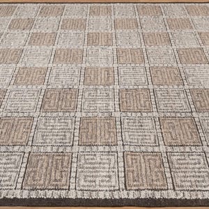 May include: A square area rug featuring a repeating grid pattern of alternating light beige and off-white squares. Each square contains a dark brown geometric Greek key motif. The entire rug is bordered by a solid dark brown trim.