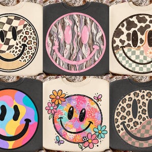 May include: Six crewneck sweatshirts featuring large circular smiley face graphics. Designs include checkered, leopard print, cow print, floral, and abstract colorful patterns on cream and charcoal gray fabric backgrounds with black outlines.