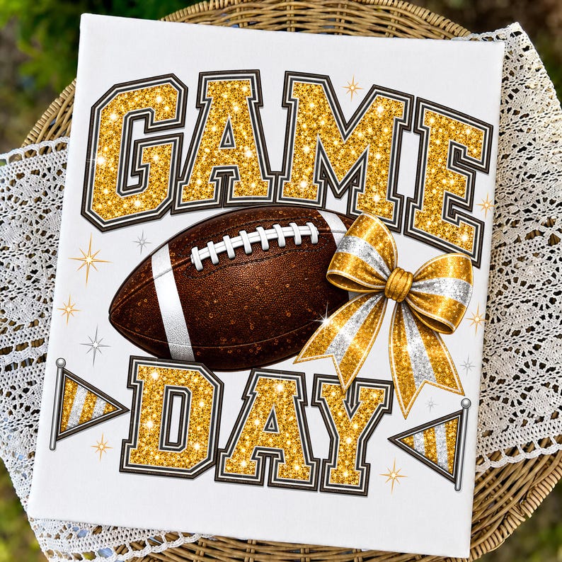 May include: A white rectangular sign featuring the text GAME DAY in large gold glitter block letters. A brown football with white laces sits in the center, accompanied by a gold and silver glitter bow and two small pennant flags on the sides.
