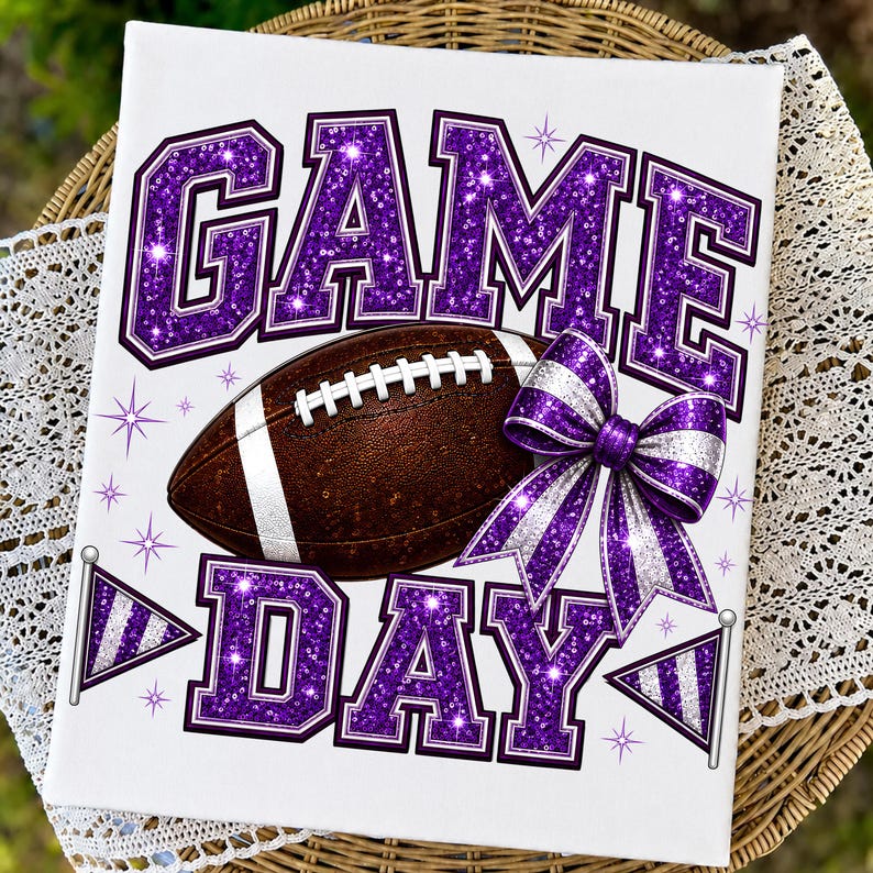 May include: A rectangular white sign featuring the text GAME DAY in large purple glitter letters. A brown football with white laces is centered between the words. A purple and silver striped bow and two small pennant flags are included.