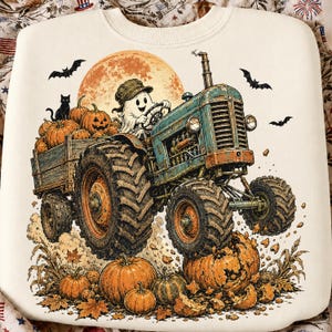 Puede incluir: Una sudadera color crema con el gr&aacute;fico de un fantasma con gorra conduciendo un tractor azul vintage. El tractor tira de un remolque lleno de calabazas y un gato negro. Murci&eacute;lagos vuelan frente a una gran luna naranja con calabazas.