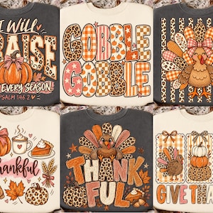 May include: A collection of six crewneck sweatshirts featuring autumn-themed graphic prints. Designs include pumpkins, turkeys, and fall foliage in orange, pink, and brown tones with text such as I Will Praise Him, Gobble Gobble, and Give Thanks.
