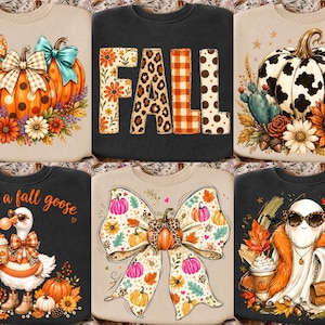 May include: A collection of six sweatshirts featuring seasonal graphics including pumpkins with bows, the word FALL in patterned letters, a cow print pumpkin, a goose wearing sunglasses and a scarf, a large bow with pumpkins, and a ghost with a purse.