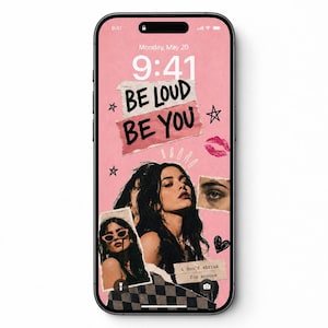 May include: A smartphone displaying a pink digital wallpaper featuring a collage of a person with dark hair, a close-up of an eye, and text that reads BE LOUD BE YOU and i don't shrink for anyone, accented with hand-drawn stars, lips, and hearts.