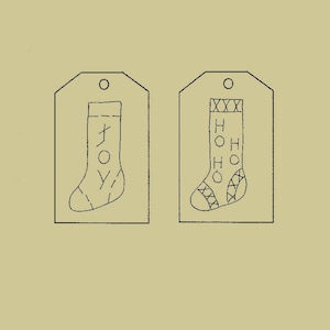 Op de afbeelding: Twee zwart-witte kerstsok-cadeauetiketten. Eén etiket heeft het woord "JOY" op de sok geschreven en het andere etiket heeft de woorden "HO HO HO" op de sok geschreven.