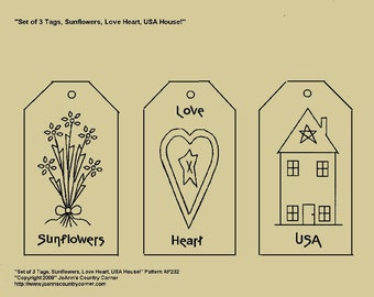 May include: Set of three decorative tags with black outlines. The tags feature drawings of sunflowers, a heart with a star, and a house with a star on the roof. The word "Sunflowers", "Love", and "USA" are written on the tags.