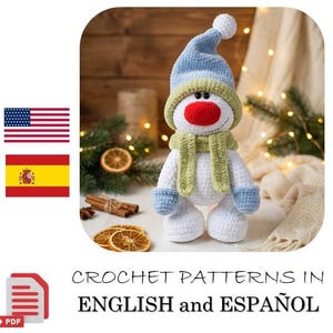 May include: A crocheted snowman doll featuring a white body, a bright red nose, and a light blue hat with a pom-pom. The snowman wears a light green scarf and matching light blue mittens. The text reads CROCHET PATTERNS IN ENGLISH and ESPAÑOL.