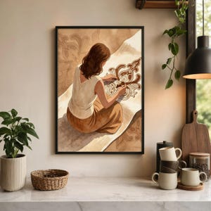 May include: A framed wall art print depicting a person with brown hair wearing a white sleeveless top and a brown skirt, sitting and drawing a brown ornate floral pattern on a large piece of paper against a light brown background.