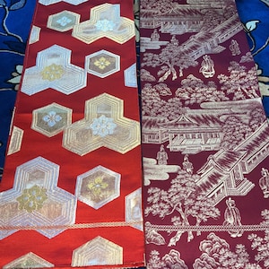 Può includere: Due pannelli di tessuto rettangolari con complessi motivi intrecciati. Il pannello sinistro è rosso brillante con motivi geometrici esagonali argentati e dorati. Il pannello destro è bordeaux scuro con un paesaggio dettagliato di edifici e alberi.