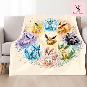 May include: A cream-colored throw blanket featuring a circular watercolor illustration of nine different Eevee evolution characters. Each character is surrounded by a unique floral and elemental aura, arranged in a ring around a central Eevee figure.