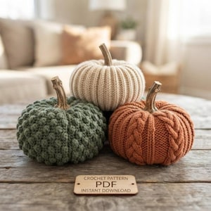 May include: Three decorative pumpkins made of yarn with brown stems. One is sage green with a bobble texture, one is cream with vertical ribbing, and one is burnt orange with a cable knit pattern. A rectangular sign reads CROCHET PATTERN PDF INSTANT DOWNLOAD.