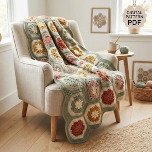 May include: A crochet blanket made of hexagonal motifs in shades of sage green, mustard yellow, dusty pink, and cream. The blanket features a floral-inspired pattern and is draped over a light-coloured upholstered armchair. Text reads DIGITAL PATTERN PDF.