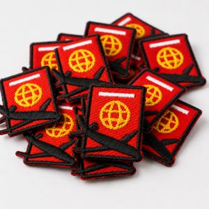 May include: A collection of rectangular embroidered patches featuring a red background, a white horizontal bar at the top, a yellow globe icon in the center, and a black silhouette of an airplane flying diagonally across the lower portion.