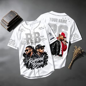 May include: A white baseball jersey featuring a graphic print of two men in sunglasses, the text "Raymond & Brown," "The R&B Tour," and "YOUR NAME" with the number 26. The design includes signatures, a microphone icon, and a stylized city skyline.