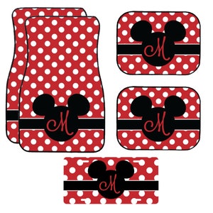 May include: Set of red and white polka dot car mats with black Mickey Mouse head designs and the letter "M" in red. Includes two front mats, two rear mats, and a license plate frame.