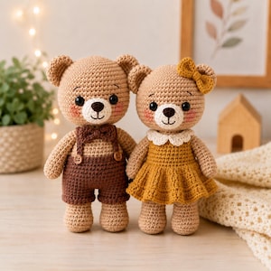 May include: Two crocheted teddy bears standing side by side. The left bear wears dark brown overalls with a matching bow tie and two small buttons. The right bear wears a mustard yellow dress with a white collar and a matching bow on its head.