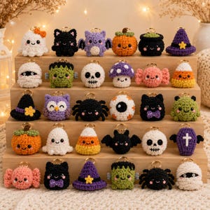 May include: A collection of thirty small, crocheted Halloween-themed keychains arranged on a wooden display stand. The figures include ghosts, pumpkins, skulls, bats, spiders, witches' hats, candy corn, mummies, and monsters in various colors.
