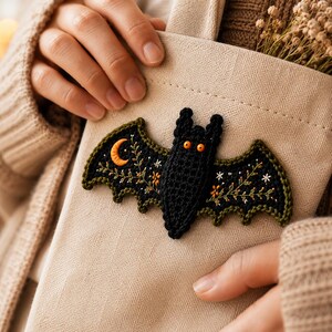 Handmade crochet bat ornaments with embroidered wings, moons, stars and floral details displayed as seasonal Halloween home decor