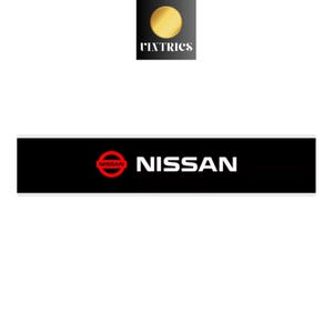 Może przedstawiać: Prostokątna czarna naklejka z czerwonym logo Nissan po lewej stronie i białym napisem NISSAN po prawej. Nad naklejką znajduje się małe kwadratowe logo ze złotą ikoną słońca i białym napisem VINTRICS umieszczonym poniżej.