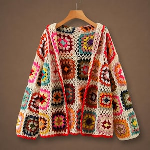 May include: A long-sleeve cardigan made of multicolored crochet granny squares in shades of red, blue, yellow, pink, and green, joined by an off-white lattice pattern. The garment features a red crocheted border along the front opening and hem.