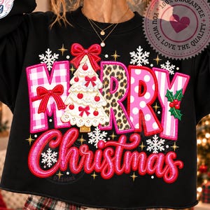Könnte beinhalten: Ein schwarzes Langarm-Sweatshirt mit einem grafischen Aufdruck, der Merry Christmas liest. Die Buchstaben sind mit rosa Vichy-Karo, Leopardenmuster und Punkten verziert. Ein weißer Weihnachtsbaum mit roten Schleifen ist mittig platziert.