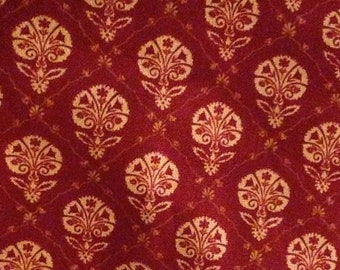 May include: A red fabric with a repeating pattern of gold floral designs. The fabric has a subtle texture and a rich, deep red color.