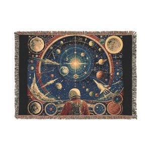 May include: A rectangular woven throw blanket featuring a detailed space scene with a central sun, various planets, and two rockets. An astronaut in a red suit and white helmet is depicted from behind, looking toward the celestial display.