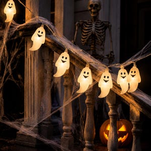 May include: A string of white, glowing ghost-shaped lights with black eyes and mouths. The translucent plastic figures are connected by a thin wire, creating a warm illumination. Each ghost features a simple, friendly expression, designed for decorative lighting.