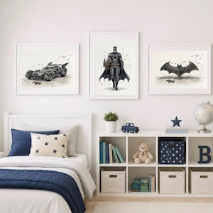 Op de afbeelding: Drie ingelijste wandprints met Batman-thema's. De linkerprint toont een zwarte Batmobile, de middelste print toont een staande Batman-figuur en de rechterprint toont een zwart vleermuisvormig embleem, alles tegen een witte achtergrond.