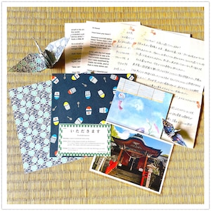 Op de afbeelding: Een verzameling briefpapier met twee origami-kraanvogels, een brief met Engelse en Japanse tekst, donkerblauw papier met patronen van schaafijs, een kaart met de tekst Itadakimasu en een foto van een rode Japanse tempel.