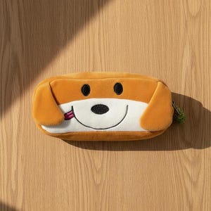 Peut inclure: Une trousse à crayons rectangulaire en peluche en forme de visage de chien. L'étui est principalement brun doré avec un museau blanc, des yeux et un nez brodés en noir, et une petite langue rose qui dépasse. Il possède des oreilles tombantes.
