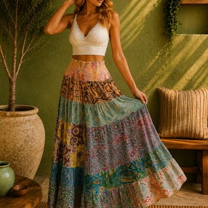 Op de afbeelding: Een wit kanten crop top met een V-hals gecombineerd met een lange, gelaagde maxirok met een patchworkontwerp van diverse kleurrijke bloemen- en paisley-patronen in tinten roze, blauw, geel en bruin met een elastische tailleband.