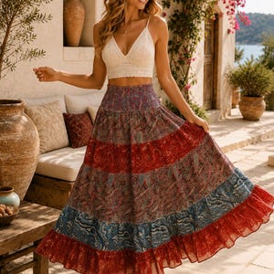 May include: A white crochet crop top with a V-neckline paired with a high-waisted, ankle-length skirt featuring a tiered design. The skirt displays a multi-colored paisley pattern in shades of red, blue, and purple with a ruffled hemline.