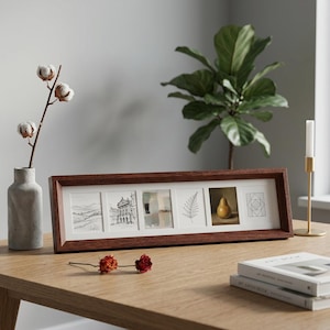 May include: A rectangular wooden picture frame containing six individual square art prints. The prints feature a landscape sketch, an architectural drawing, an abstract painting, a fern leaf illustration, a pear painting, and a geometric line design.