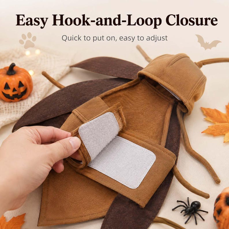May include: A brown insect-themed pet costume featuring a hood with antennae and large dark brown wings. The garment includes an easy hook-and-loop closure for adjustment. Text on the image reads: Easy Hook-and-Loop Closure, Quick to put on, easy to adjust.