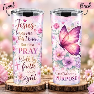 Op de afbeelding: Een cilindrische beker met een doorzichtig deksel en een roze en paars aquarel bloemendesign. De voorzijde toont de tekst Jesus loves me this I know But first PRAY Walk by faith not by sight. De achterzijde toont een vlinder en Created with a PURPOSE.