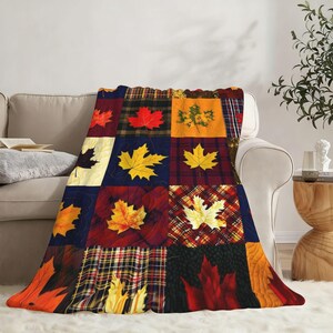 May include: A soft throw blanket featuring a patchwork design of various autumn maple leaves in shades of red, orange, yellow, and brown. The pattern includes alternating squares of solid colors, plaid, and textured backgrounds with maple leaf motifs.